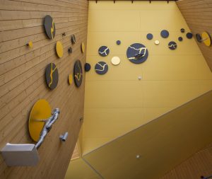 Julkinen taideteos jossa pyöreitä mustia ja oransseja muotoja kiinni päiväkodin seinässä sekä katossa.