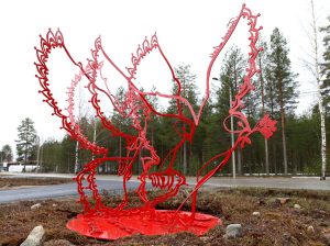 Kuvassa on punainen abstrakti veistos, jossa on linnun siipien muotoja.