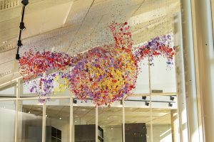 Kaltevasta sisätilan katosta roikkuu suuri määrä värikkäitä esineitä.