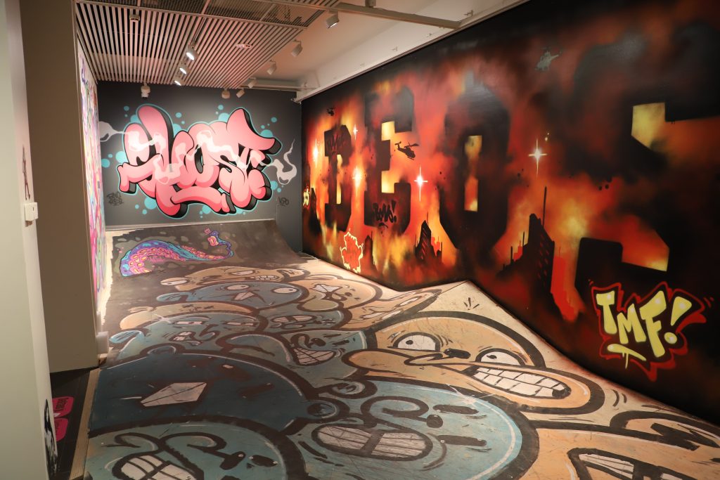 Huone, jossa on skeittausalue. Kaikki seinät ja skeittausalueen rakenteet on maalattu täyteen graffiteja.